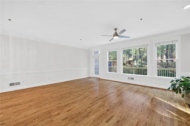 a view of an empty room with a window and wooden floor