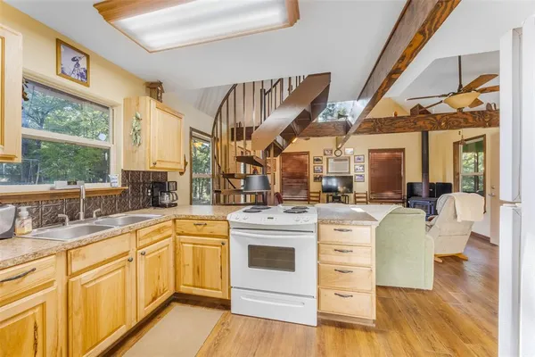 a kitchen with a stove a sink and white cabinets with wooden floors