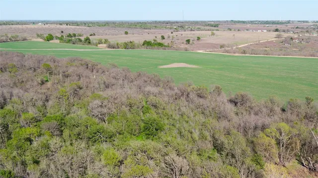 a view of a field with an ocean and house in background