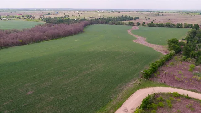 an aerial view of a houses with outdoor space and trees all around