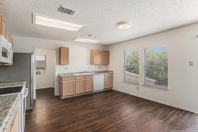 a kitchen with granite countertop a stove top oven a sink dishwasher and a fireplace with wooden floor