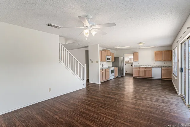 a view of an empty room with wooden floor and a ceiling fan