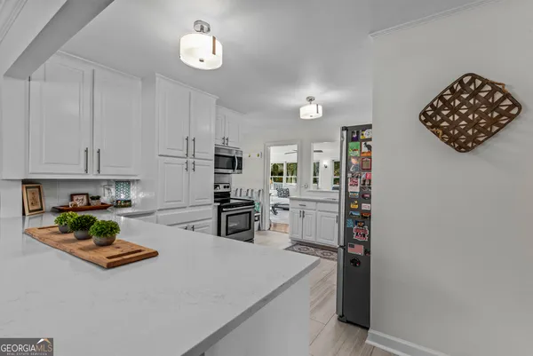 a kitchen with stainless steel appliances white cabinets a sink a stove a microwave and wooden floors