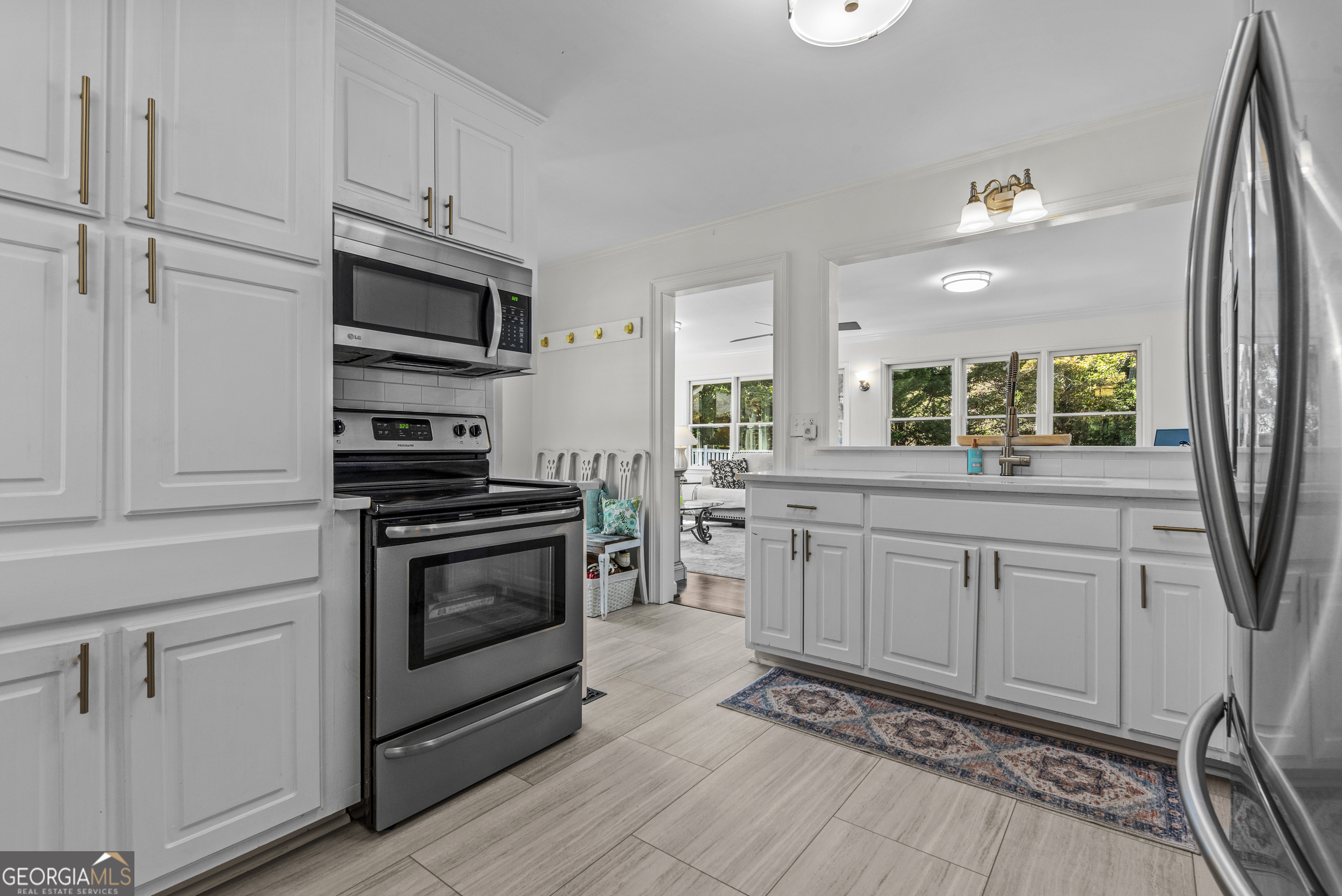 991 Old Post Road Madison, GA 30650 - Photo 16 of 61 a kitchen with stainless steel appliances white cabinets a sink a stove a microwave and wooden floors