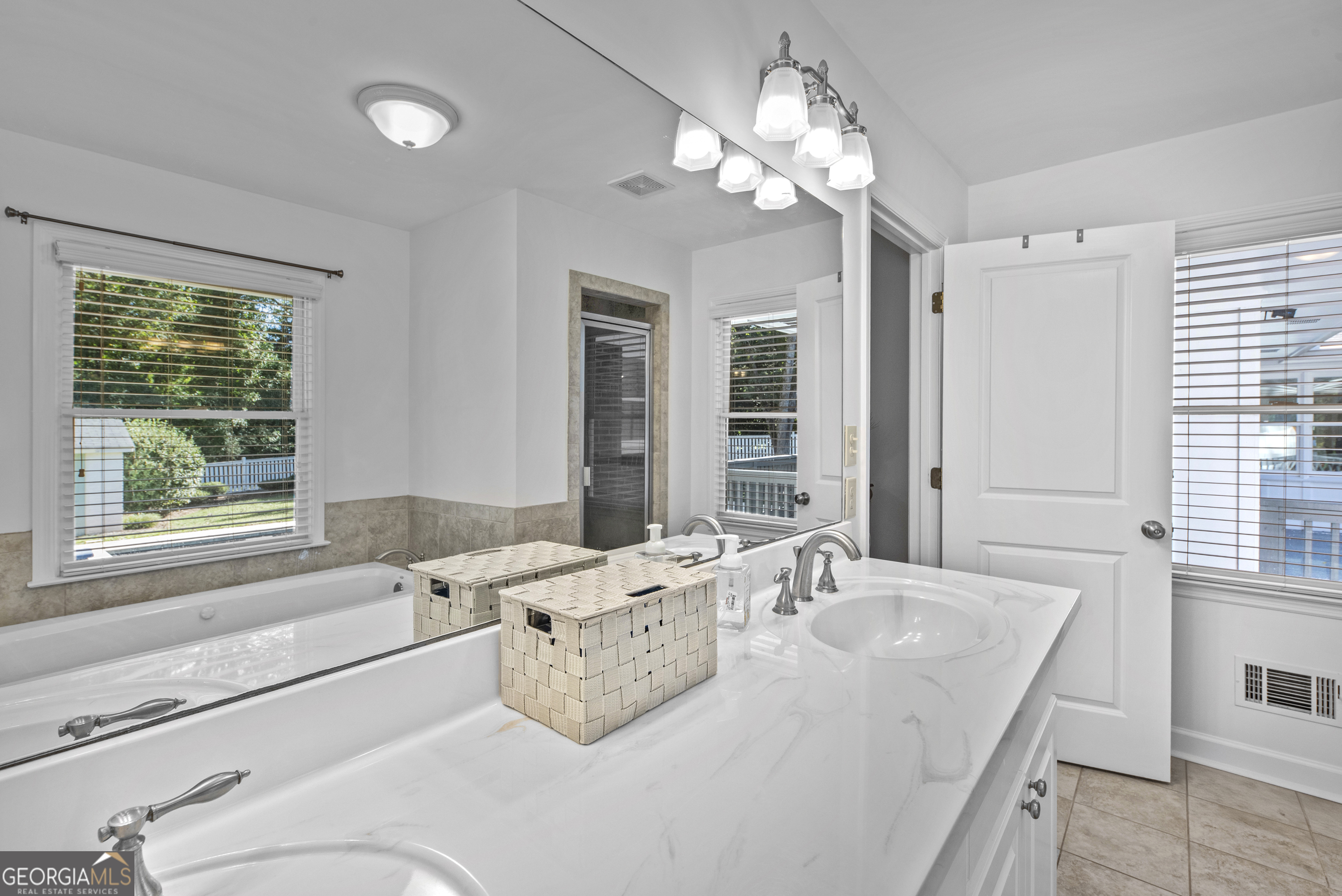 991 Old Post Road Madison, GA 30650 - Photo 38 of 61 a spacious bathroom with a granite countertop sink a large mirror and a bathtub next to a window