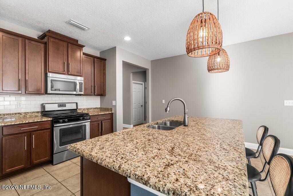 14042 Carson Court Jacksonville, FL 32224 - Photo 12 of 37 a kitchen with kitchen island stainless steel appliances granite countertop a stove top oven a sink a counter space and cabinets