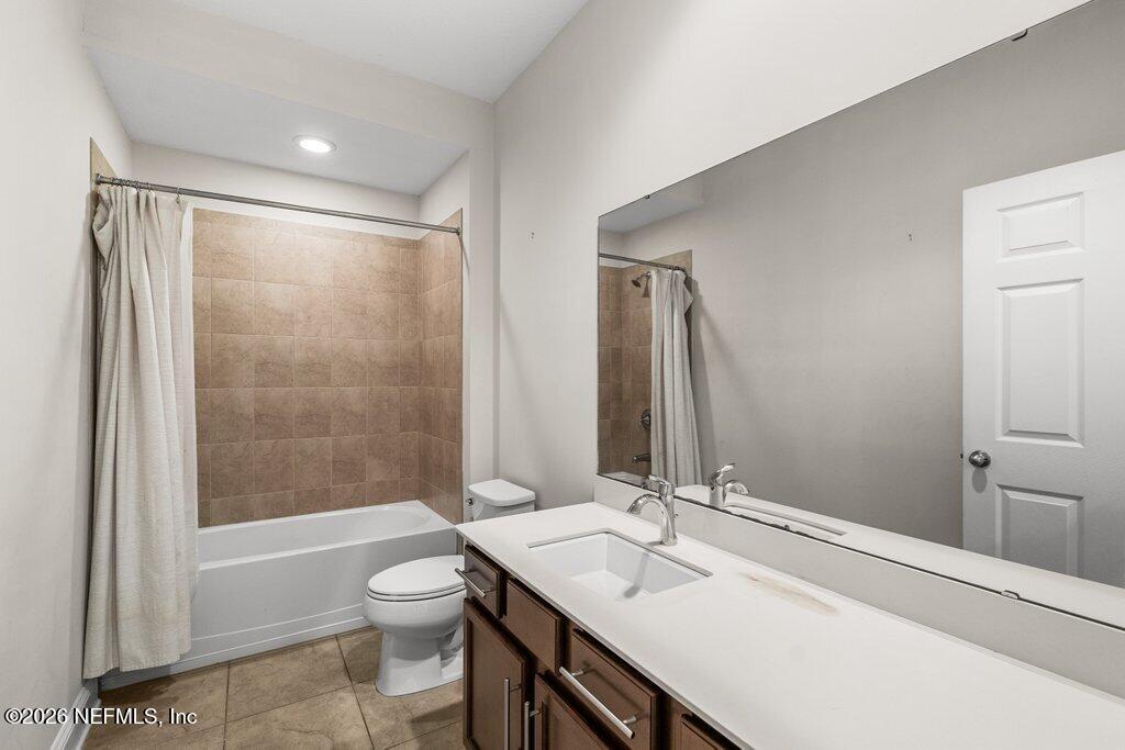 14042 Carson Court Jacksonville, FL 32224 - Photo 27 of 37 a bathroom with a granite countertop sink toilet a large mirror a bathtub and shower