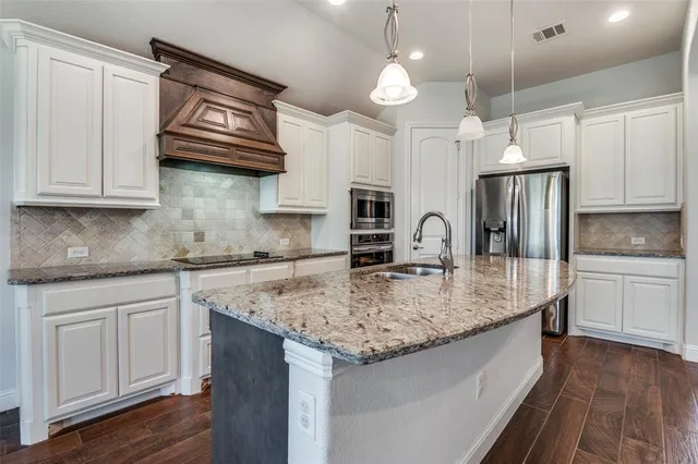 a kitchen with stainless steel appliances granite countertop a sink dishwasher and white cabinets with wooden floor