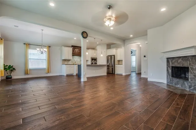an empty room with wooden floor and a kitchen
