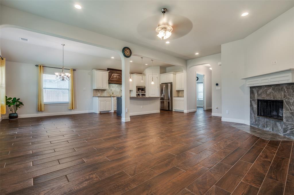 426 Summer Grove Drive Midlothian, TX 76065 - Photo 3 of 25 an empty room with wooden floor and a kitchen