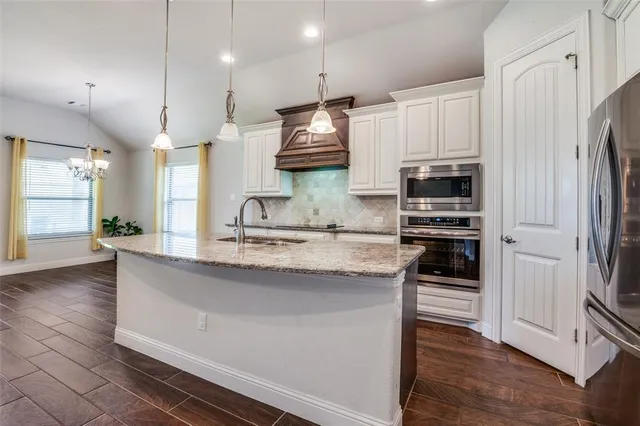 a kitchen with stainless steel appliances granite countertop a sink a stove and a refrigerator