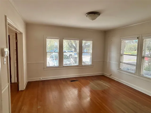 a view of an empty room with a window and wooden floor