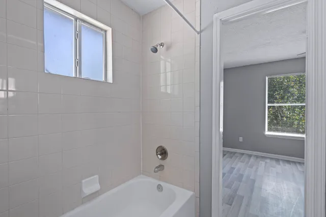 a bathroom with a tub shower and window