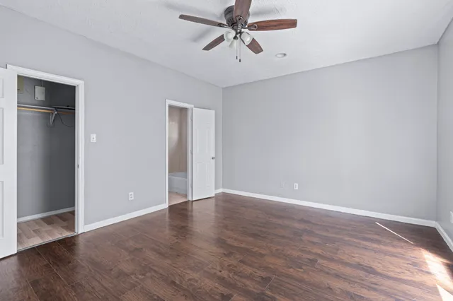 a view of an empty room with window and wooden floor