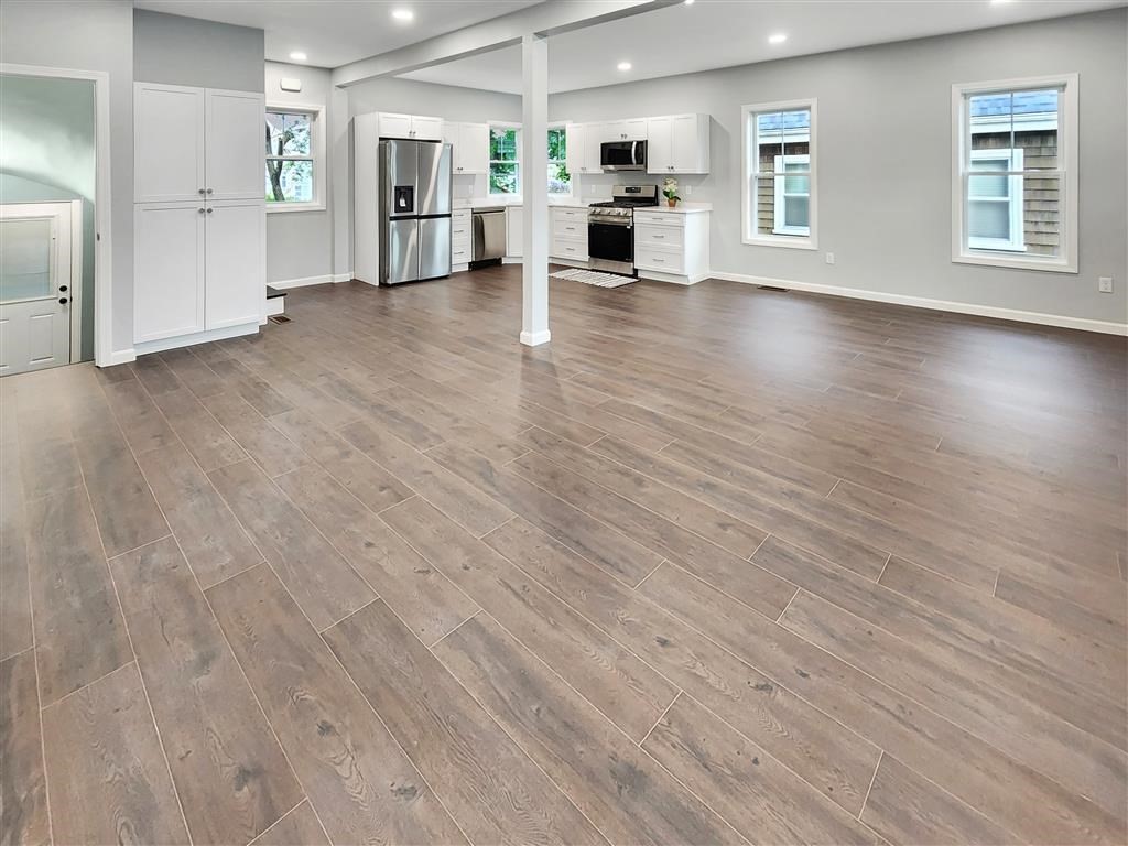 144 Rounds Street New Bedford, MA 02740 - Photo 3 of 20 an empty room with wooden floor kitchen view and windows