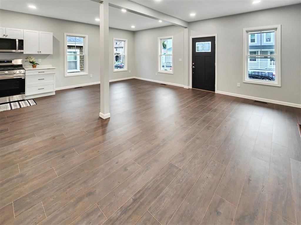 144 Rounds Street New Bedford, MA 02740 - Photo 5 of 20 a view of an empty room with a window and wooden floor