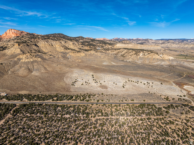 1040 West Under The Rim Road Tropic, UT 84776 - Photo 10 of 21 Expansive desert landscape featuring a paved road, scattered green vegetation, and distant mountains under a clear sky
