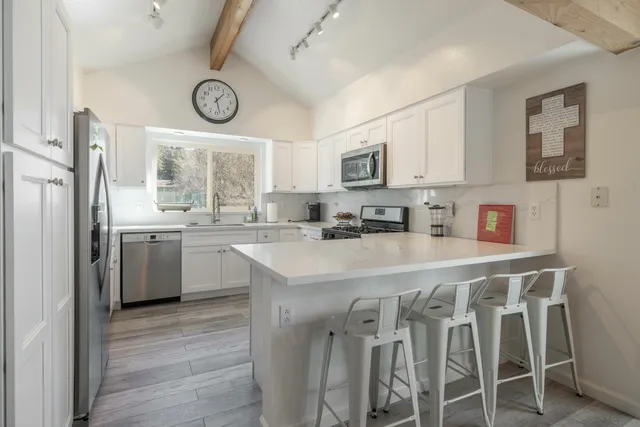 a kitchen with stainless steel appliances granite countertop a table chairs cabinets and a sink