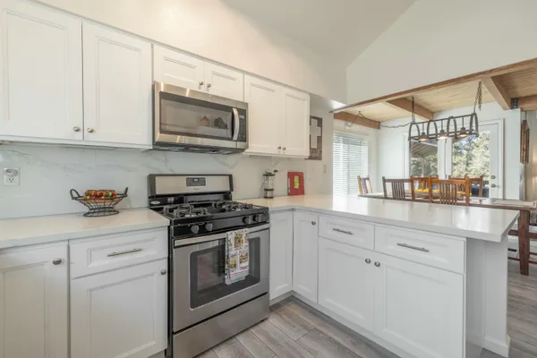 a kitchen with stainless steel appliances granite countertop white cabinets a sink and a stove