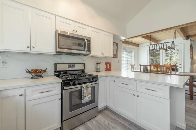 a kitchen with stainless steel appliances granite countertop white cabinets a sink and a stove