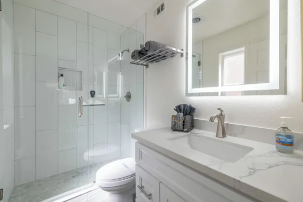 a bathroom with a granite countertop sink a toilet and shower