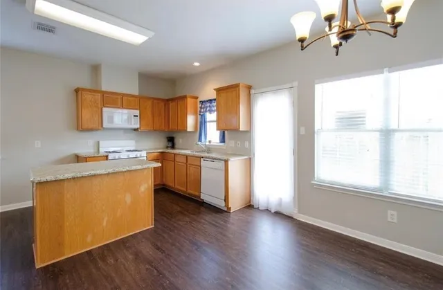 a kitchen with stainless steel appliances granite countertop a stove a sink dishwasher and a refrigerator with wooden floor