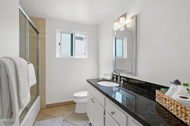 a bathroom with a granite countertop sink toilet and mirror