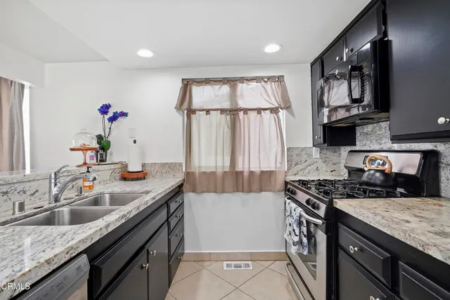 a kitchen with granite countertop a sink stove and cabinets