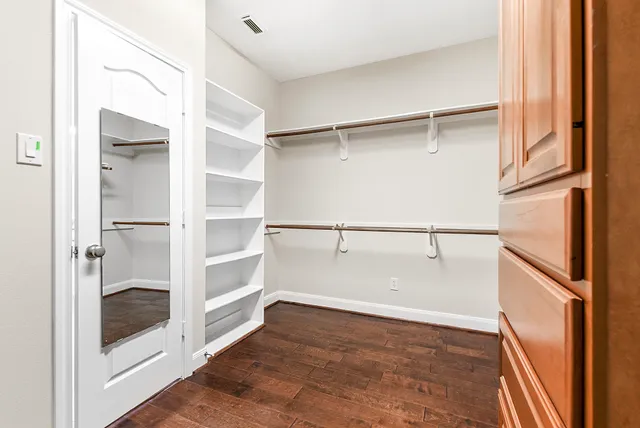 an empty room with wooden floor chandelier fan and windows