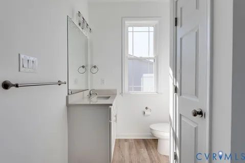 a bathroom with a granite countertop toilet a sink and a mirror