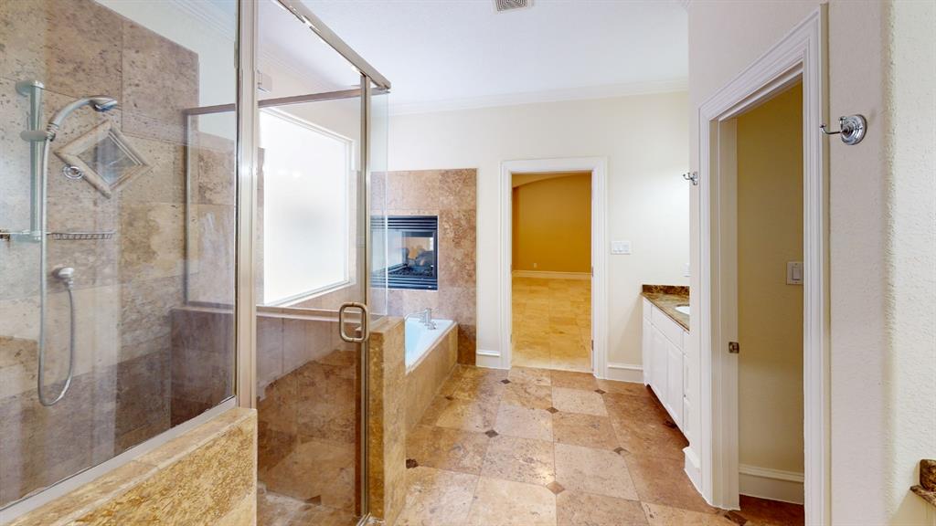 4516 Gilbert Avenue Dallas, TX 75219 - Photo 17 of 28 Bathroom featuring a glass-enclosed shower, a built-in tub with a fireplace, and a vanity with a countertop