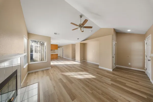 a view of an empty room with window and wooden floor