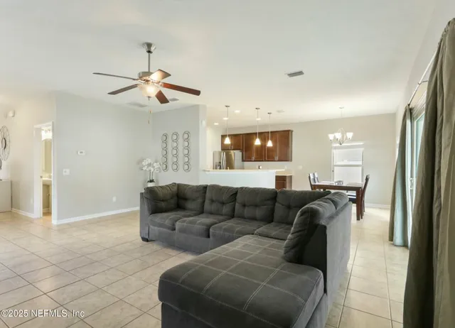 a living room with couches and kitchen view with wooden floor