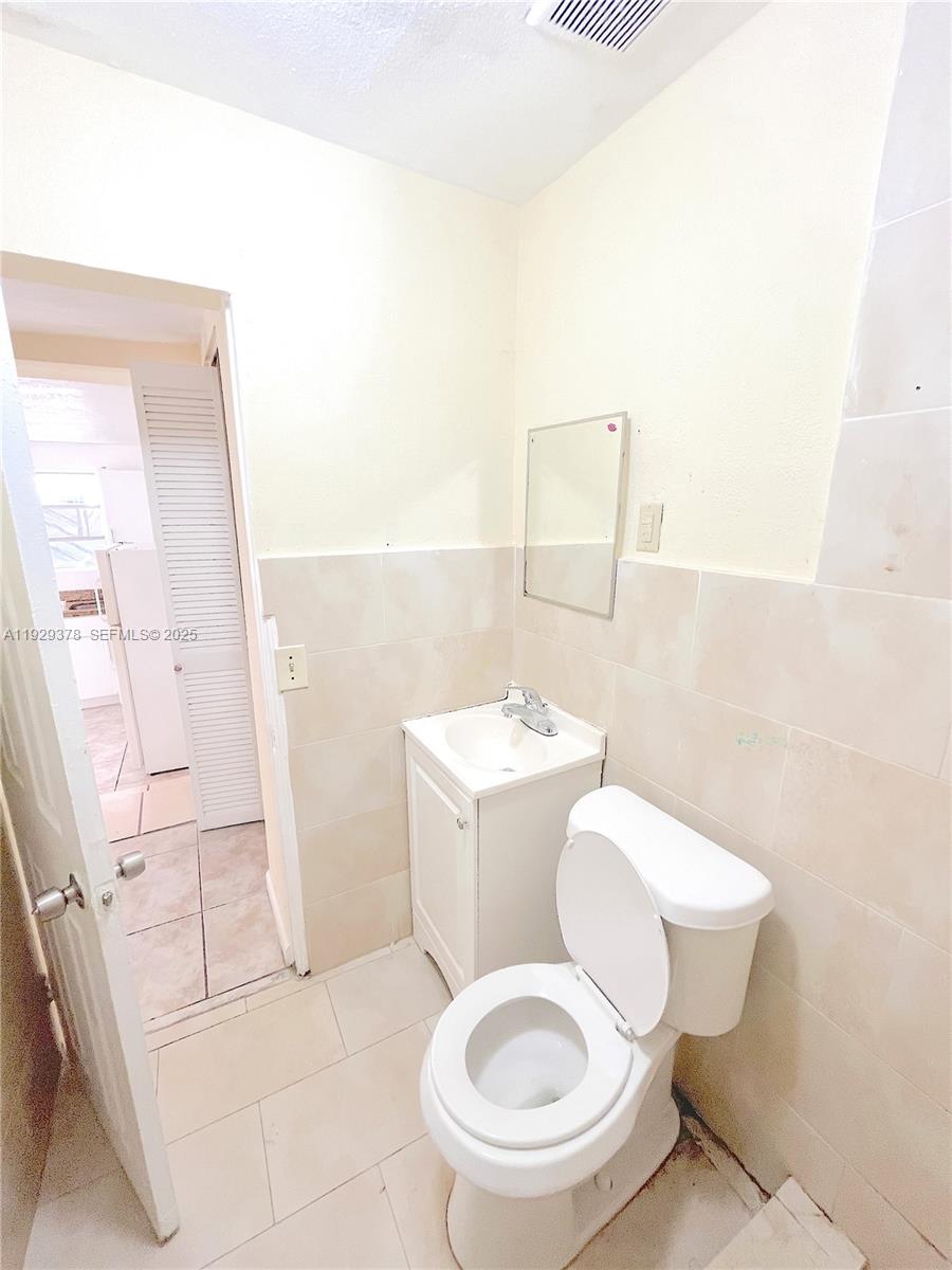 236 East 14th Street, Unit B Hialeah, FL 33010 - Photo 12 of 16 a white toilet sitting next to a bathroom sink and a mirror