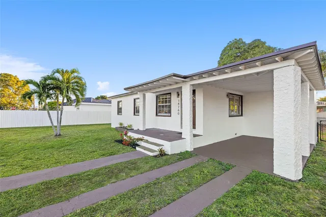 a front view of a house with a yard and potted plants