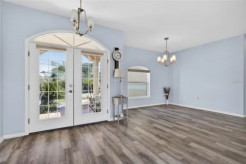 a view of an empty room and a kitchen with wooden floor