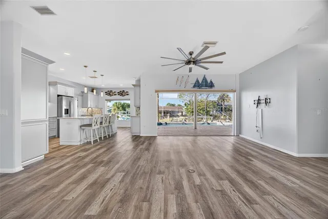 a view of empty room with wooden floor and fan