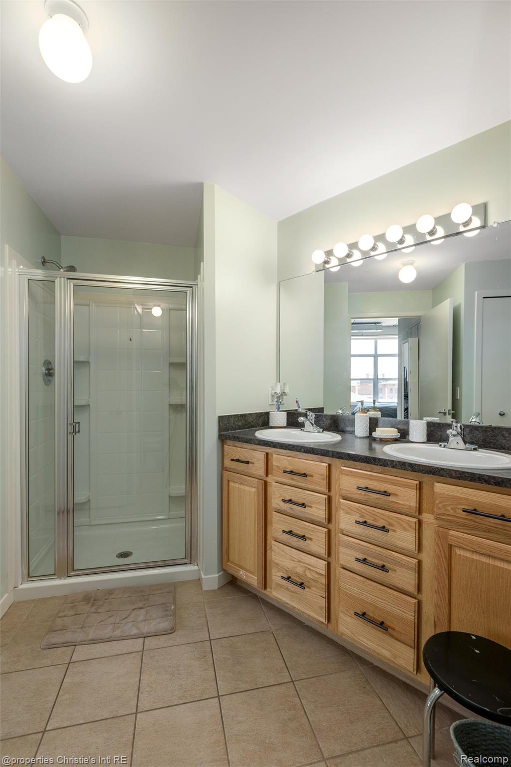 66 Winder Street, Unit 332 Detroit, MI 48201 - Photo 18 of 30 Bathroom featuring double vanity, light tile patterned flooring, and a shower stall