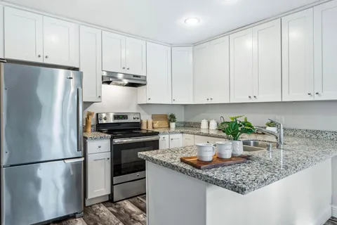 a kitchen with stainless steel appliances granite countertop a refrigerator sink and white cabinets