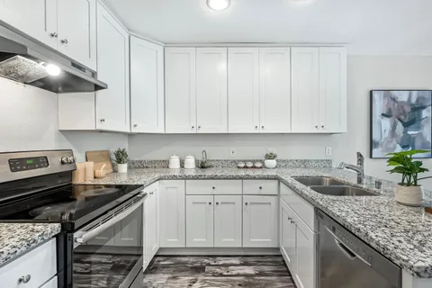 a kitchen with granite countertop a sink stainless steel appliances and cabinets