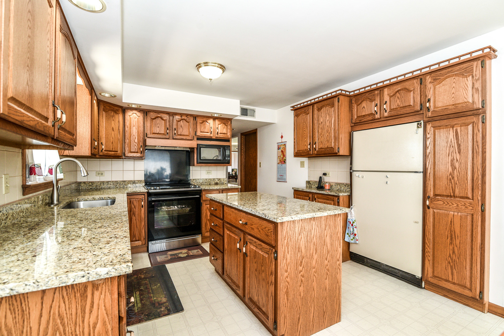 5149 State Road Burbank, IL 60459 - Photo 10 of 36 a kitchen with a refrigerator a stove top oven a sink and cabinets