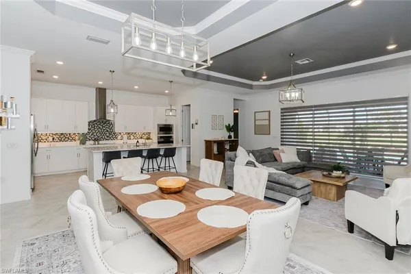 a dining room with kitchen island furniture a chandelier a large window and stainless steel appliances
