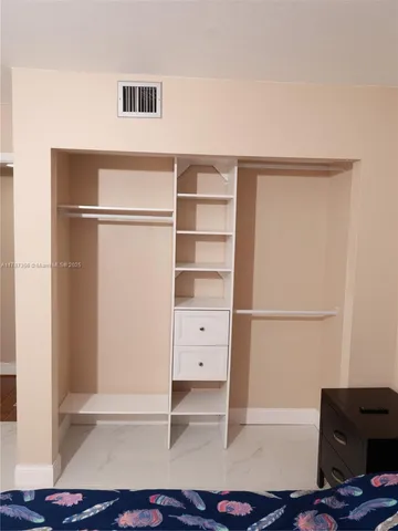 a view of an empty room with cabinet and a window