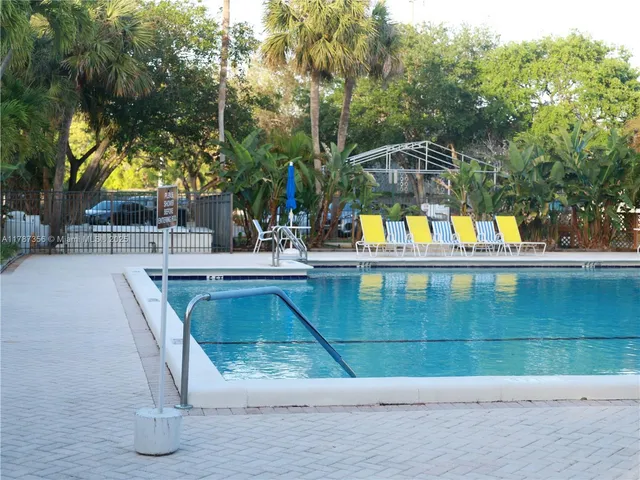 a view of a swimming pool with a lawn chairs under an umbrella
