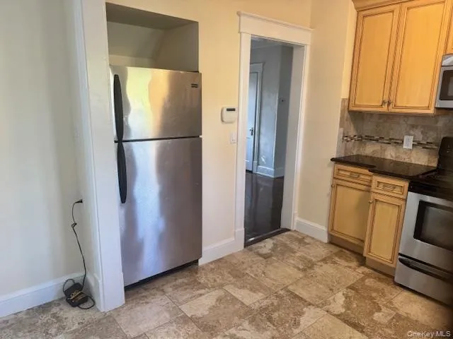 a view of a refrigerator in kitchen and an empty room
