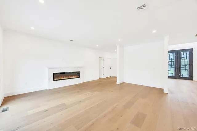 a view of an empty room with chandelier fan and wooden floor