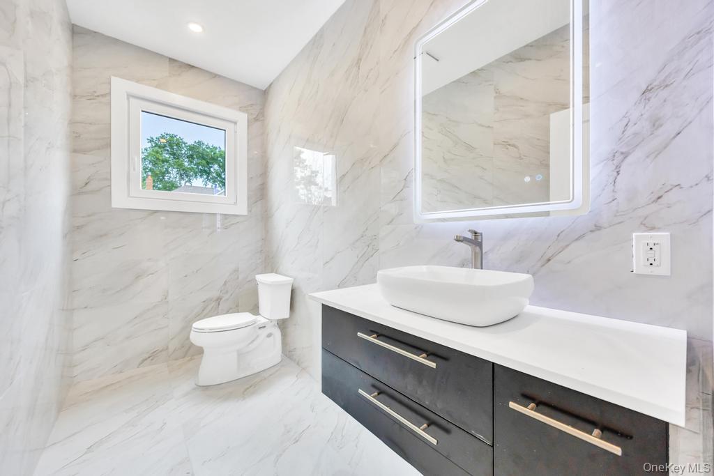 472 Farm Ranch Road East Bethpage, NY 11714 - Photo 18 of 40 a bathroom with a sink a mirror a toilet and a window