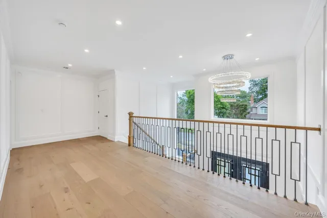 a view of an empty room with wooden floor and windows