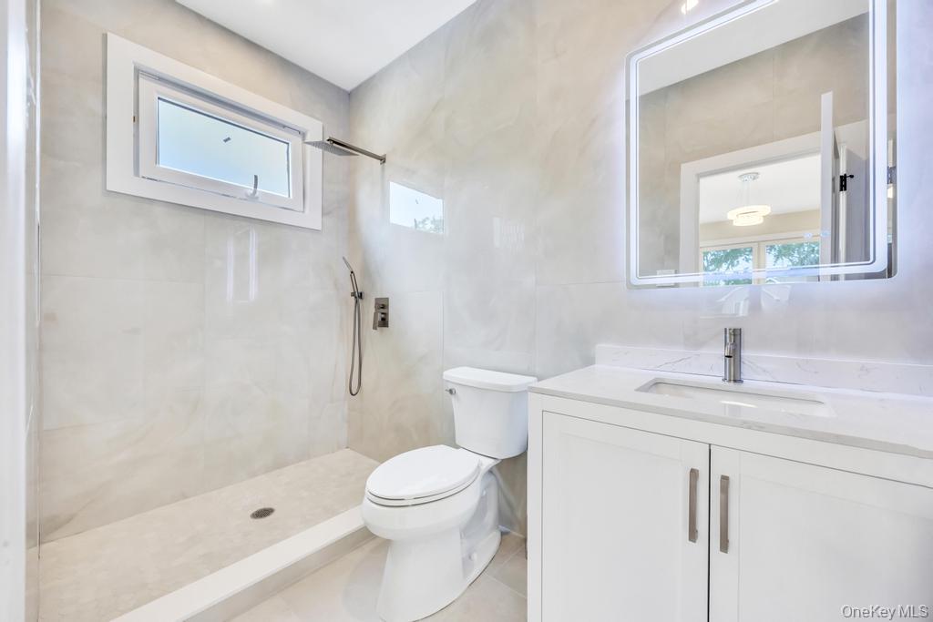 472 Farm Ranch Road East Bethpage, NY 11714 - Photo 22 of 40 Full bath with vanity, a tile shower, tile patterned floors, and tile walls