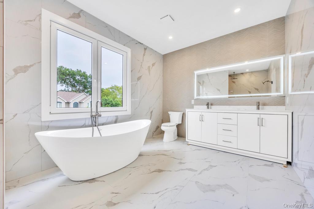 472 Farm Ranch Road East Bethpage, NY 11714 - Photo 33 of 40 Full bath featuring stone wall, double vanity, a soaking tub, marble tiled flooring, and recessed lighting